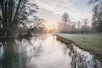 Mist rises at dawn from the River Lambourn that runs through the grounds of Welford Park, Newbury, Berks, UK