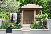 Garden building with raised beds and water feature, Iris 'Harriet Holloway', columns of Taxus baccata, Viburnum opulus - Pro Corda Trust - A Suffolk Retreat, RHS Chelsea Flower Show 2016 - Design: Frederic Whyte, Sponsor: Pro Corda Trust