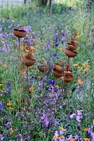 RHS Greening Grey Britain Garden. Bird feeders in wild flowers garden. Designer: Ann-Marie Powell, Sponsors: RHS Chelsea Flower Show 2016