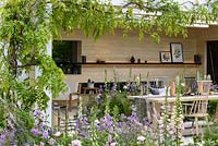 An outside-room in The LG Smart Garden, a Scandinavian lifestyle garden inspired by moden technology and softened by delicate pstel planting such as Digitalis 'Glory of Roundway' and Hesperis matronalis and framed by Wisteria 'Schowa Beni'. The RHS Chelsea Flower Show 2016 - Designer:  Hay Joung Hwang - Sponsor: LG Electronics - SILVER-GILT