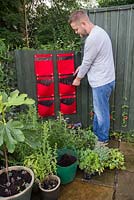 Man half filling vertical planters with compost