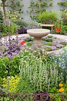 Herb garden with central bird bath. Calendula officinalis, Linum perenne, Salvia officinalis 'Greek', Atriplex hortensis var. Rubra. The St John's Hospice, A Modern Apothecary, Design Jekka McVicar. RHS Chelsea Flower Show 2016