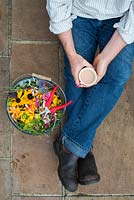 Gardener with a cup of tea after deadheading flowers - September