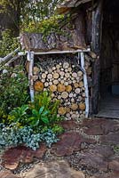 Log store and steppings stones made of tree trunks. The Woodcutter's Garden, RHS Malvern Spring Festival 2016. Design: Mark Walker
