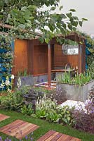 A contemporary corten steel summerhouse with integral benches and table and large metal rectangular containers. Rider on the Storm, RHS Tatton Flower Show 2011, Cheshire