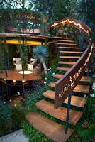 Belvedere in the Winton Beauty of Mathematics Garden lit at night, RHS Chelsea Flower Show 2016. Illuminated mathematical symbols cut into band of copper to form bannister for staircase