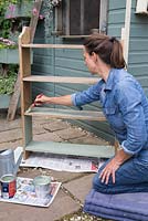 A woman painting book shelves with green paint