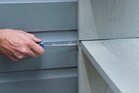 Securing the upcycled book shelf unit to a shed