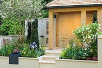 A Suffolk Retreat. An Arts and Crafts inspired garden made from natural materials, with perennials, Iris 'Jane Philips' and Viburnum opulus. Sponsor: The Pro Corda Trust. Designer: Freddy Whyte. RHS Chelsea Flower Show 2016