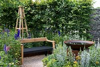 An Arts and Crafts inspired garden room with water feature, hornbeam hedge and hand crafted bench surrounded by perennials. A Summer Retreat designed by Laura Arison and Amanda Waring. RHS Hampton Court Flower Show 2016