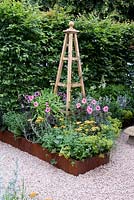 CCLA. A summer Retreat. Wooden Obelisk, Dahlia's, Achillea, Alchemilla mollis and Cosmos in shallow raised bed with rusty steel edging. Gravel pathway Designers: Amanda Waring and Laura Arison Sponsors: CCLA. RHS Hampton Court Palace Flower Show 2016