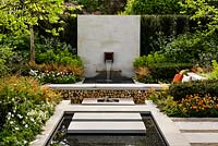 Graduate Gardeners 'Sunken Retreat' Garden - view showing reflecting pool, sawn Yorkstone paving, firewood storage bench, Corten steel fire pit, water feature and mixed planting - RHS Malvern Spring Show 2016. Designer: Ann Walker.