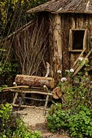 Rustic wooden hut, saw horse, logs and woodland planting - The Woodcutter's Garden - RHS Malvern Spring Show 2016. Designer: Mark Walker, Sponsor: Howards Motors