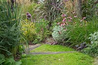 Chamomile path with railway sleepers. Border containing Artemisia, Echinacea, Verbena bonariensis and ornamental grasses