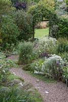 Overview of the White Garden, featuring gravel path leading past variegated grasses and perennials