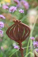 A rusty metal Allium sculpture amongst Pennisetum
