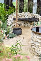Sandstone wall with a wooden seating and planting of Agave, Stipa tenuissima. Great Gardens of the USA: The Austin Garden, RHS Hampton Court Flower Show in 2016. Designer: Sadie May Stowell - Sponsor: Brand USA