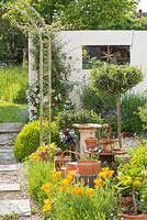 Courtyard garden with box topiary, lavender, Eschscholzia californica, wirework arch, found objects and improvised sculptures.