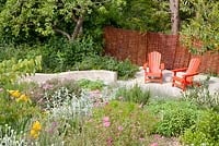 Decorative painted red garden seats on patio with Cistus, Iris and Stachys 