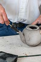 Using a conical, foam diddler, Stephen cleans out the teapot spout.