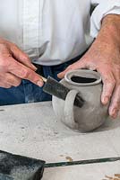 Using a triangular foam diddler, Stephen smooths the seams beneath the teapot handle.