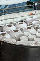 Cooling in a kiln, unglazed teapots and mugs known as 'biscuitware', after biscuit firing which hardens the clay ready for hand decoration.