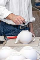 Stephen stamps the bottom of the teapot with the logo for Aston Pottery.