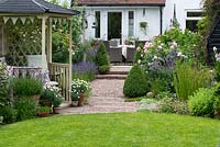 A gazebo is placed a third of the way down a 24m x 7.6m town garden. Above, a rising pebble path lined in lavender and roses leads to a terrace