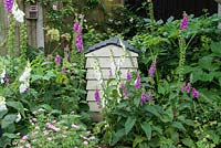 A compost bin in the shape of a beehive is set in a shady corner, and enclosed in foxgloves.