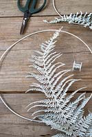 Attaching sprayed fern leaf to metal ring with thin wire