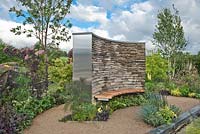 The Cruse Bereavement Care: A Time for Everything garden at RHS Chatsworth Flower Show 2017. Drystone wall with wooden bench seat, water feature rill channel, hardstanding area with island beds of herbaceous perennials, shrubs and treesDesign: Neil Sutcilffe