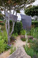 The RHS watch This Space garden. Large rocks and metal structures with crushed stone paths. Designer: Andy Sturgeon. RHS Hampton Court Palace Flower Show 2017