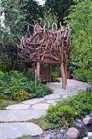 The Zoflora and Caudwell Children's Wild Garden. Tree house made from driftwood. Designers: Adam White and Andree Davies, Sponsors: Zoflora. RHS Hampton Court Palace Flower Show 2017