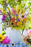 Jug of summer perennials. Echinacea purpurea, Agastache 'Black adder', persicaria 'Firetail', Verbascum densiflorum, Hellenium, Monarda, Achillea filipendulina 'Gold Plate', Galium verum, Lavandula angustifolia, Lythrum salicaria, Sanguisorba officinalis, sunflower, Centranthus ruber.