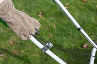 Pulling starter cord on motor mower, rotary grass cutter