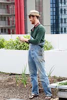 Gardener with straw hat and overall at the rooftop kitchen garden in the centre of Rotterdam, Holland.