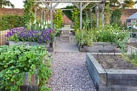 A greenhouse and raised beds for fruit, vegetables and cut flowers in a modern Cheshire country garden. It was designed by Louise Harrison-Holland. Plants include strawberries, Salvia viridis and Antirrhinums.