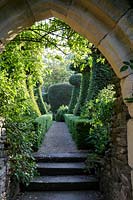 Hanham Court Gardens, Bristol. Early summer garden. Arch leading to topiary avenue