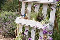 White pallet planter with garden tools and a mix of flowers, grasses and herbs