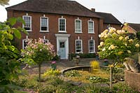The front of the house dates to Queen Anne and is planted with standard roses 'Anne Boleyn' and 'Graham Thomas'