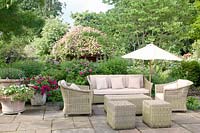 Wicker furniture on patio in summer with Rosa and mixed decorative containers