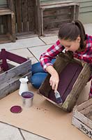 Young girl painting inside of wooden crate