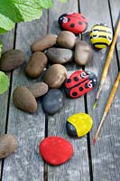 Garden craft making painted Bumble bees and Ladybirds with stones.  Paint the stones the solid base colour - red for the Ladybirds or yellow for the Bumble bees