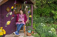 Young girl sat in front of decorated playhouse