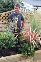 Antony Henn from Garden on a roll by newly planted borderof mature plants where plants are placed according to the paper plan for the designed border