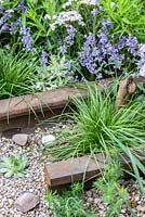 Piece of rusty railway track, gravel, pebbles, Euphorbia cyparissias 'Fens Ruby' and grasses. Gravel garden with Achillea millefolium 'Wonderful Wampee', Nepeta racemosa 'Walker's Low', Euphorbia characias 'Tasmanian Tiger' and sempervivum. By The Sea - RHS Hampton Court Palace Flower Show 2017 - Design: James Callicott - Sponsor: Southend Borough Council.