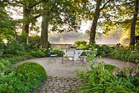 Garden set on circular gravel patio in wood area. Design: Dina Deferme