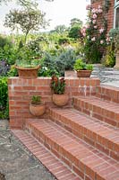 The brick steps are decorated with ceramic pots both freestanding and hung from the wall