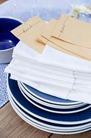 Blue crockery and white napkins with pockets folded to put a name card in them for dressing the table