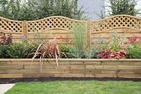 Raised bed with shrub and perennials supplied by Gardens on a Roll